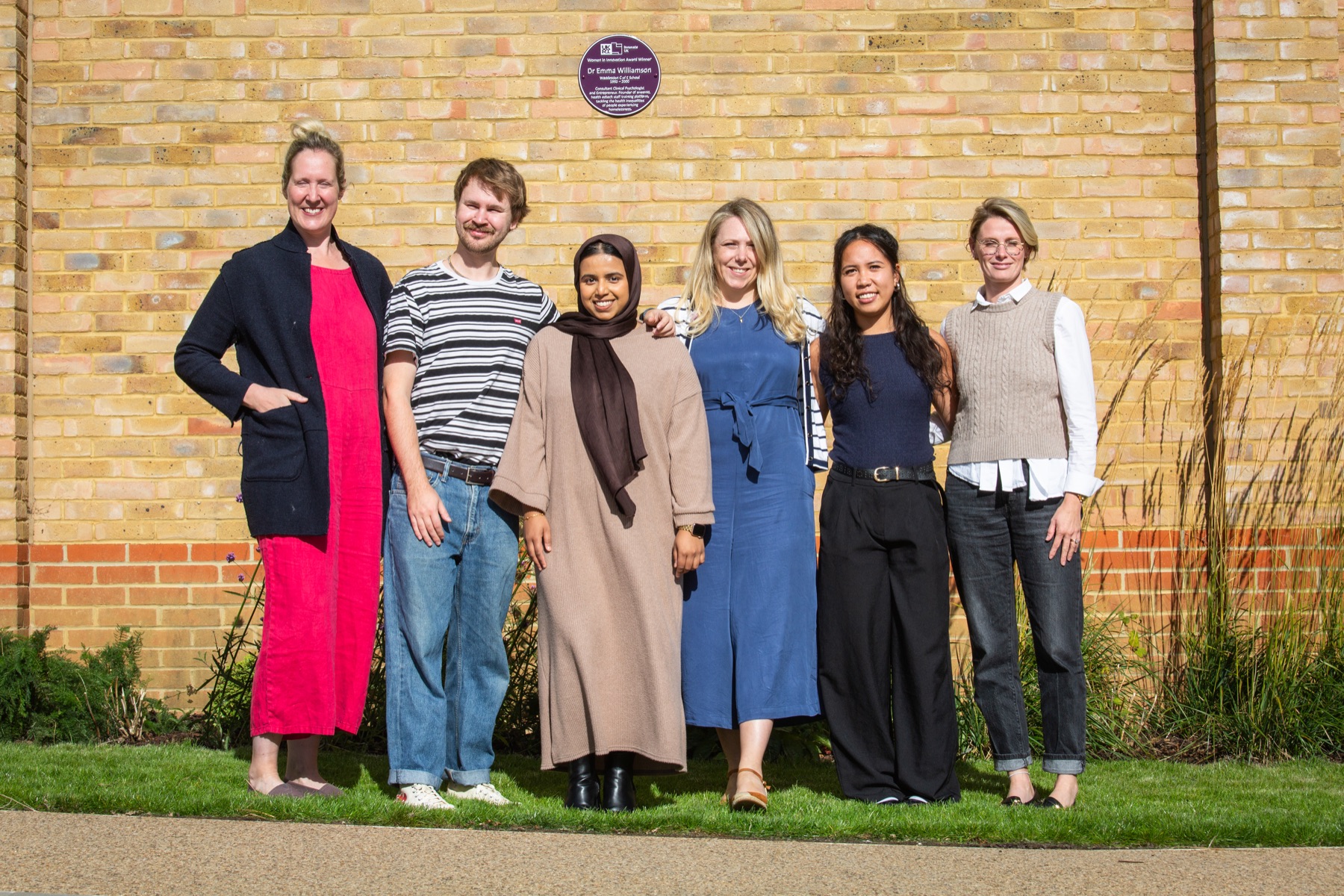 The aneemo team outside a brick building beneath a purple plaque
